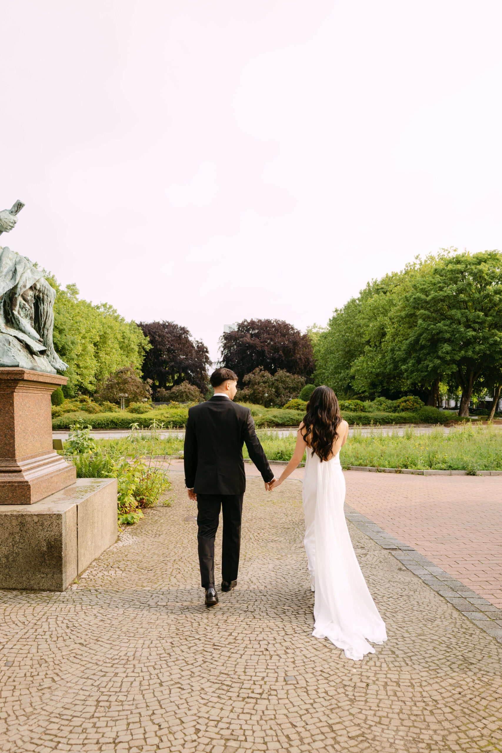 Das Brautpaar geht Hand in Hand über den Vorplatz des Rathaus Hamburg nach ihrer standesamtlichen Hochzeit beim Brautpaarshooting mit Hochzeitsfotografin Laura Kaiser